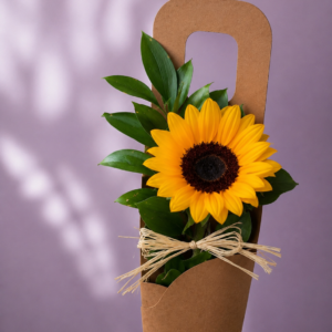 Girasol en formato transportable con follaje verde y envoltorio kraft.