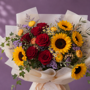 Ramo floral con girasoles, rosas rojas, flores amarillas y follaje verde en envoltorio decorativo.