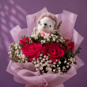 Ramo de rosas rojas con gipsofila, follaje verde y peluche decorativo en envoltorio rosado.