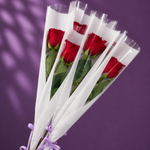 Rosas individuales rojas con envoltorio blanco, acabado transparente y lazo lila.