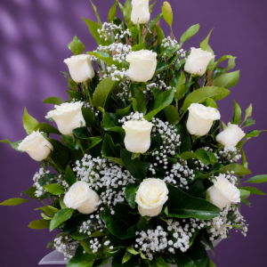 Pie de urna con 12 rosas blancas, follaje verde y gipsofila en un elegante arreglo floral.