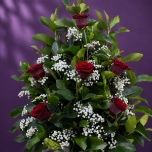 Pie de urna con 6 rosas rojas, follaje verde y gipsofila en un elegante arreglo floral.